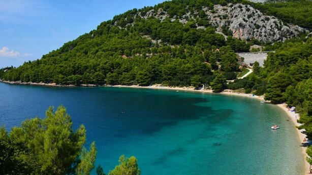 A coastal area with a clear turquoise sea, a sandy beach, and dense green forested hills. - 5 stars, Family Apartment  Pero at Nature park close to Adriatic sea (Peracko Blato/Ploce)