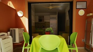 A dining area with a table and chairs, a potted plant, and a view into a kitchen. - B124 Seaside view Las Vistas TRG Tenerife Royal Gardens (Playa de la Américas)