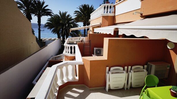 A balcony with white railings, a green chair, and a table. - B124 Seaside view Las Vistas TRG Tenerife Royal Gardens (Playa de la Américas)