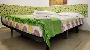 A neatly made bed with a green throw blanket, a stack of folded towels, and a painting of a couple on the wall. - B124 Seaside view Las Vistas TRG Tenerife Royal Gardens (Playa de la Américas)