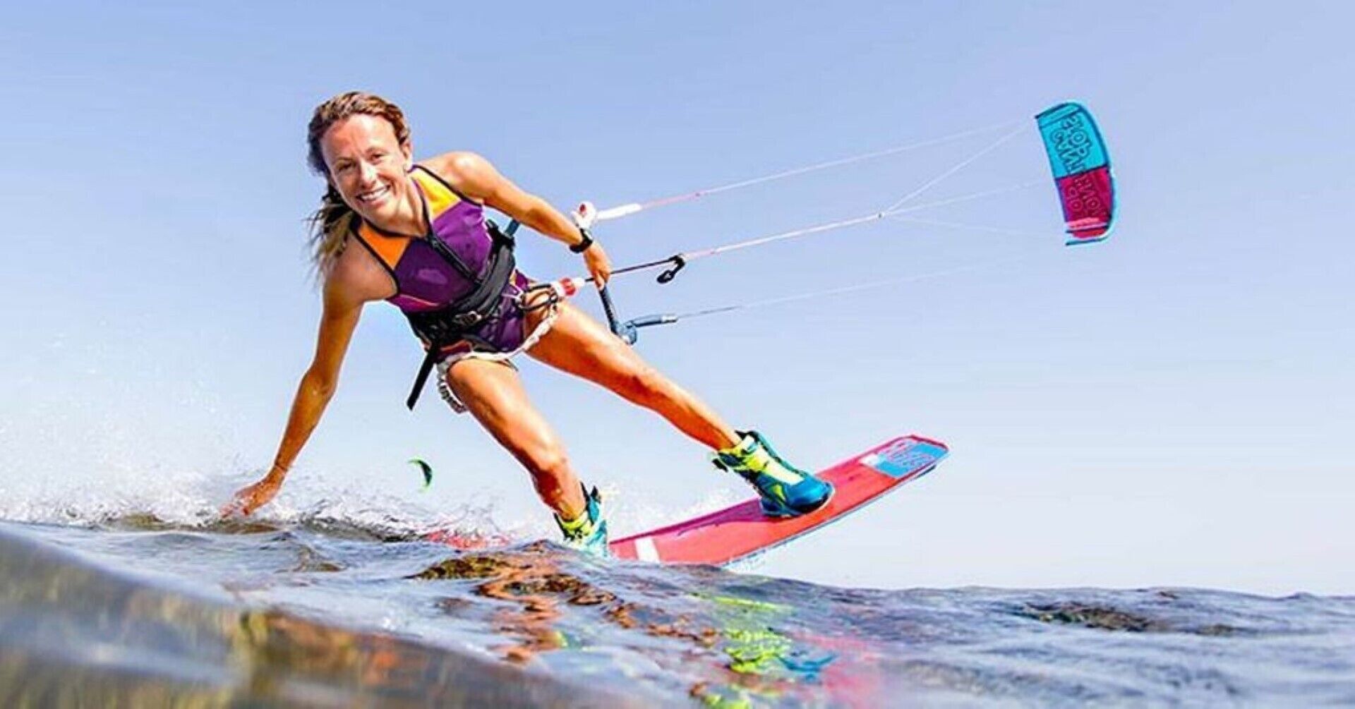 Iemand windsurft op een board met een kleurrijk ontwerp.