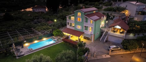 A two-story house with a swimming pool, a covered patio, and a staircase leading to the upper floor.
