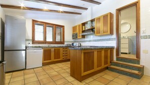 A kitchen with wooden cabinets, a built-in microwave, and a dishwasher. - CASABRA - Villa with private pool in Urb. Monterrey, Palma de Gandia. Free WiFi (Palma de Gandia)
