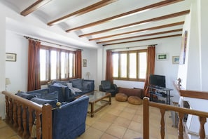 A living room with a sofa set, a television, and a staircase.