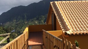 A wooden staircase leading to a balcony with a tiled roof, overlooking a mountainous landscape. - Yellow Attic S. Vincent (São Vicente)