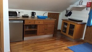 A compact kitchen with wooden cabinets, a built-in microwave, and a sink. - Yellow Attic S. Vincent (São Vicente)
