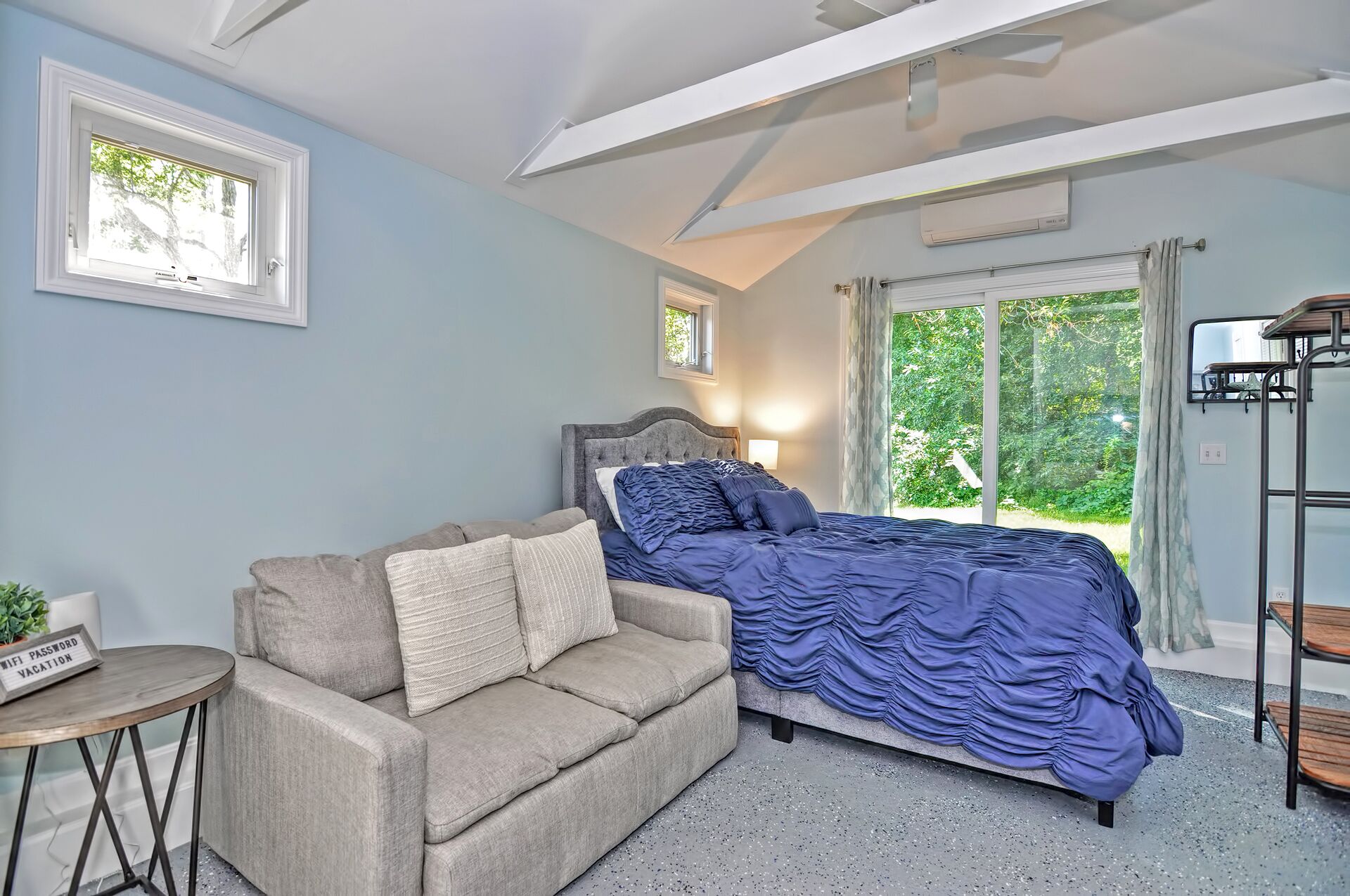 A bedroom with a bed, a sofa, a small table, and a window with curtains.