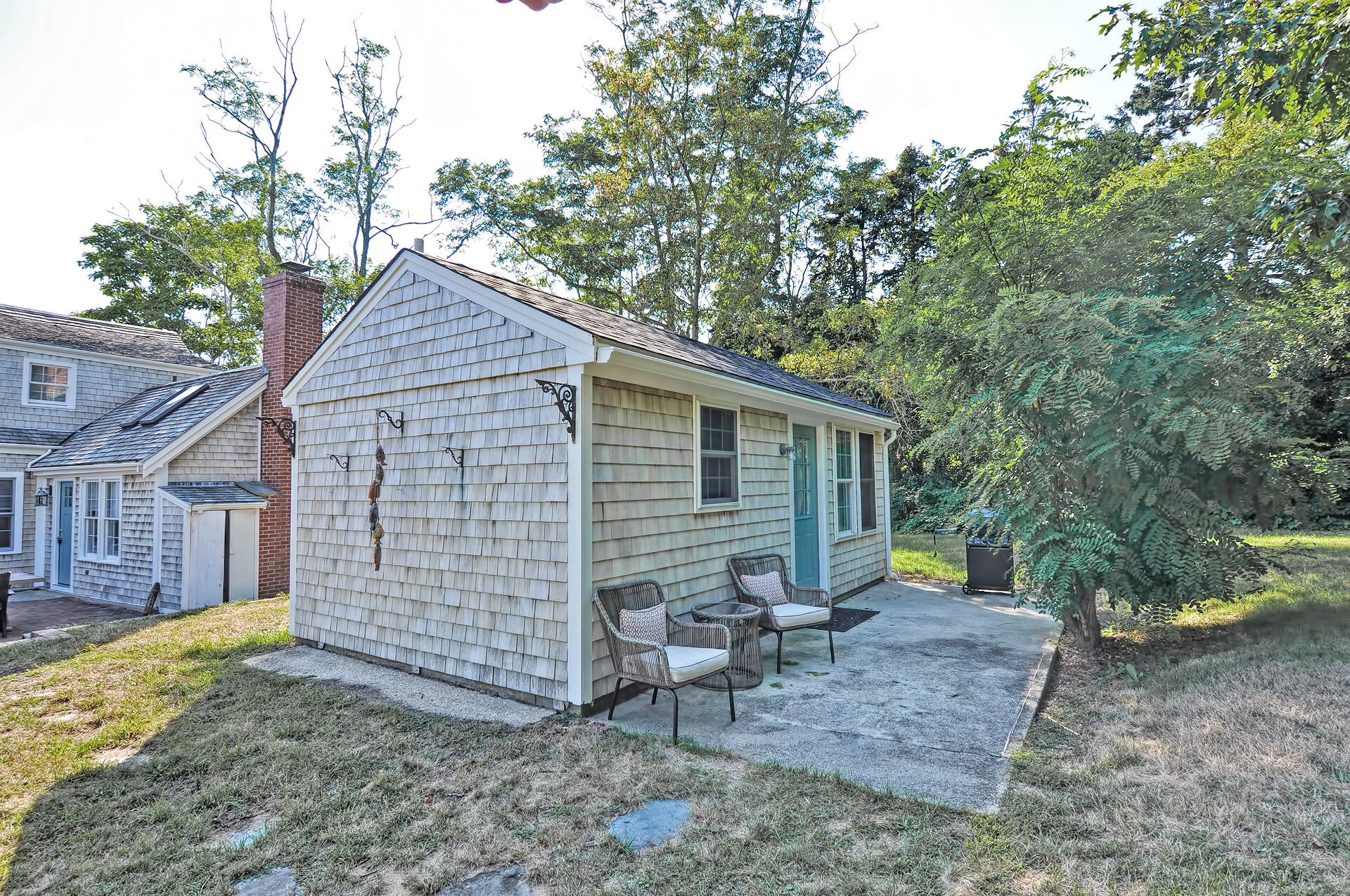 A small, single-story house with a front porch and two chairs.