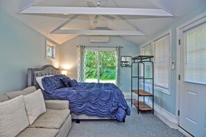 Un dormitorio con cama, sofá, ventilador de techo y ventana con persianas.
