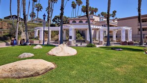 Un patio con palmeras, una pérgola y un edificio con techo de tejas.