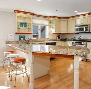 A kitchen with a large island, wooden cabinets, stainless steel appliances, and a window.