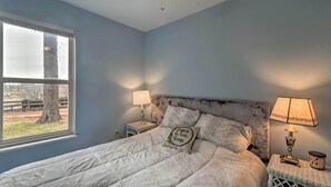 A bedroom with a bed, two bedside tables, a window, and a ceiling fan.