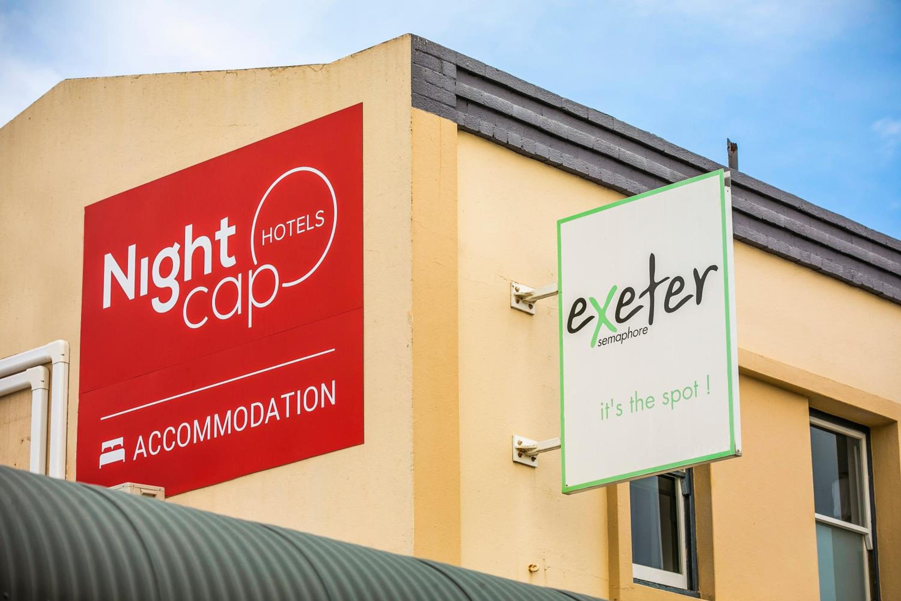 A building with a red sign for Nightcap Hotels and a white sign for Exeter, indicating accommodation availability.