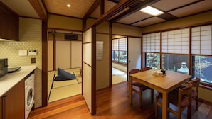 A traditional Japanese room with tatami flooring, a wooden table, and a view of a garden through a shoji screen. - Utaimachi (Kanazawa)