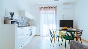 A modern kitchen with white cabinets, a microwave, and a dining area with a table and chairs.