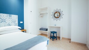 A bedroom with a bed, a desk, and a hanging coat rack.