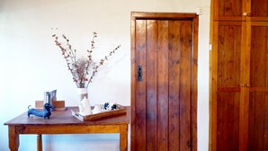 Un tavolo di legno con un vaso di rami secchi, un vassoio con delle figurine e una porta in legno.