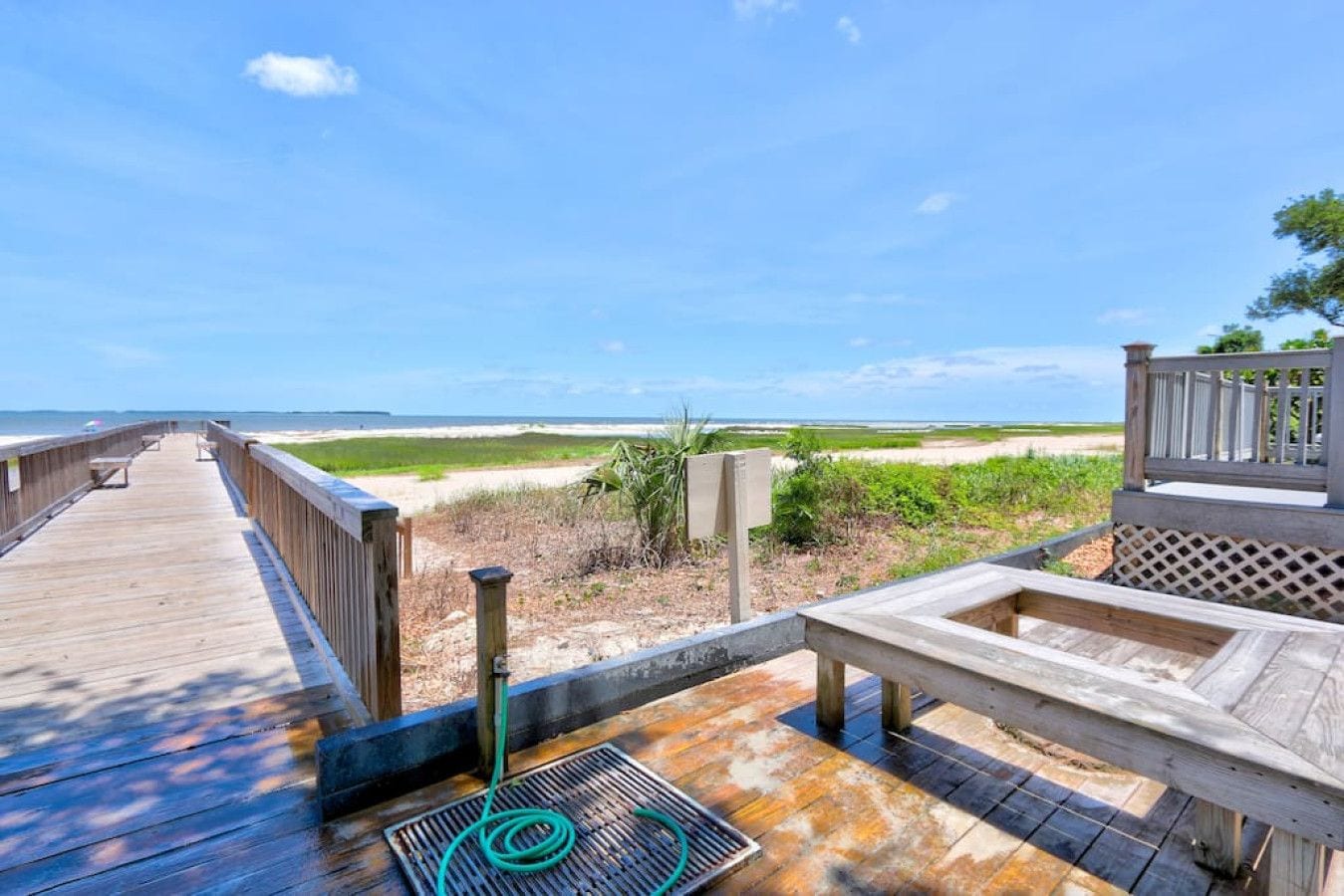 A wooden boardwalk leading to a beach with a view of the ocean.