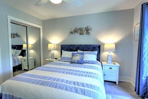 A bedroom with a bed, nightstands, a mirror, and a ceiling fan.