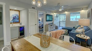 Una sala de estar moderna con una mesa de comedor de madera, un sofá azul y un televisor montado en la pared.