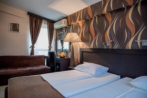 Una camera d'albergo con un letto, un divano, una scrivania e una parete con motivo ondulato.