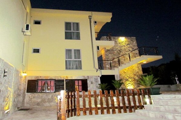 Un edificio a più piani con facciata in pietra, una scala in legno e un balcone con ringhiere.