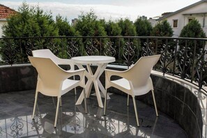 Een ronde tafel met vier stoelen op een balkon met een metalen hekwerk.