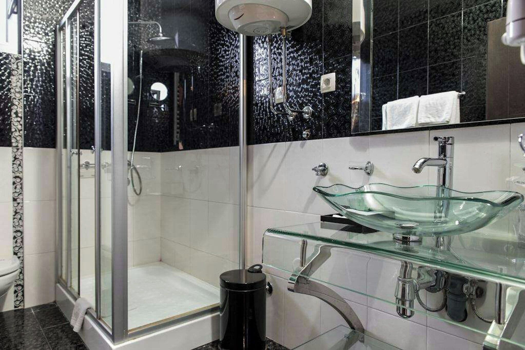 Un bagno moderno con lavabo in vetro, cabina doccia e WC.