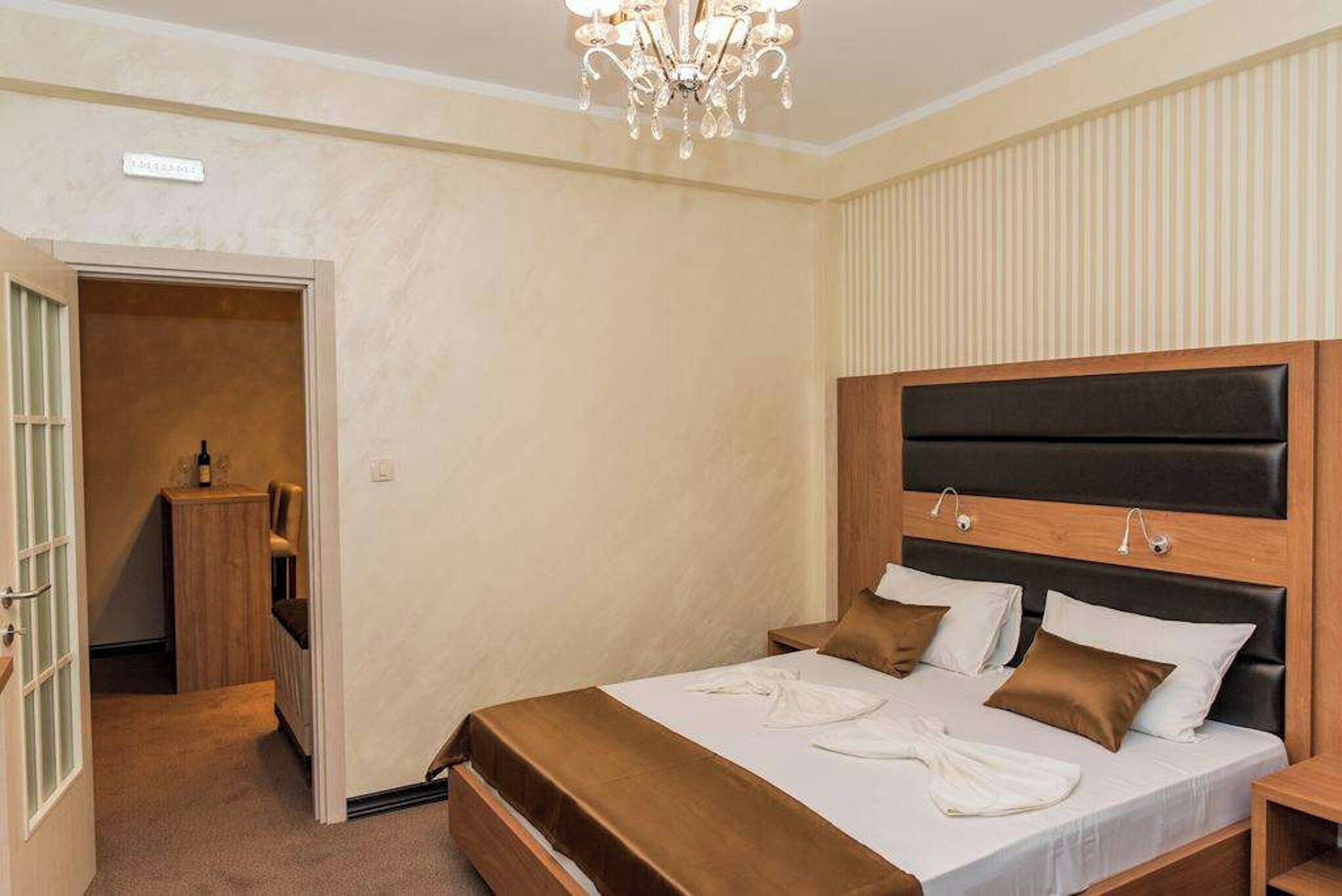 A hotel room with a bed, bedside table, and a chandelier.