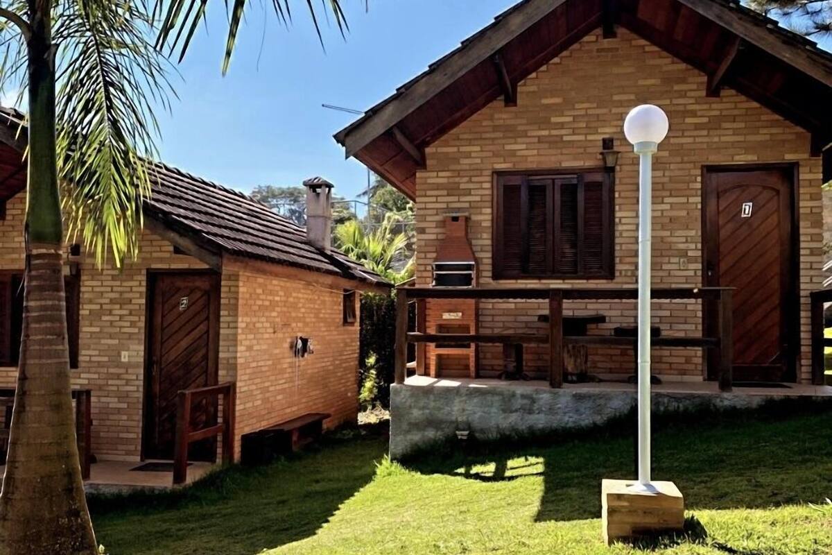 Una casa de ladrillo con puerta y contraventanas de madera, un pequeño patio y un farol.