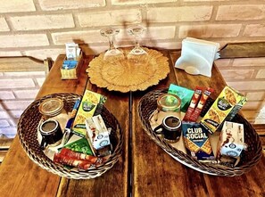 Två korgar av rotting står på ett träbord, och på bordet finns det också snacks, drycker och en dekorativ tallrik.