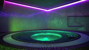 A circular hot tub with a tiled floor and a wall-mounted control panel. - TeoDorka Med & Spa (Ciechocinek)