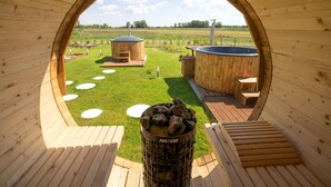 A wooden structure with a circular opening, a hot tub, and a fire pit. - TeoDorka Med & Spa (Ciechocinek)