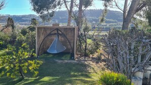 Uma cadeira suspensa num jardim com vista para colinas ao longe.