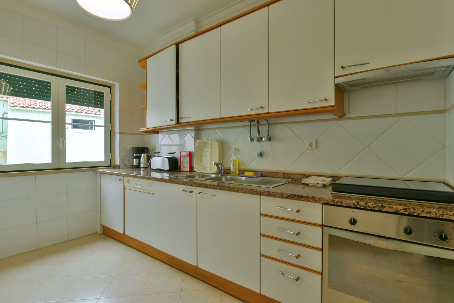 A kitchen with white cabinets, a countertop, a stove, and a window.
