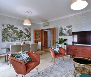 A modern living room with a TV, seating, and decorative plants. - Angle's 67 With parking Place (Lisboa)