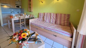 Un espacio habitable compacto con kitchenette, comedor y cama con ropa de cama a rayas.