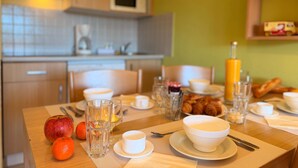 Una mesa de desayuno dispuesta con platos, tazones, vasos y frutas.