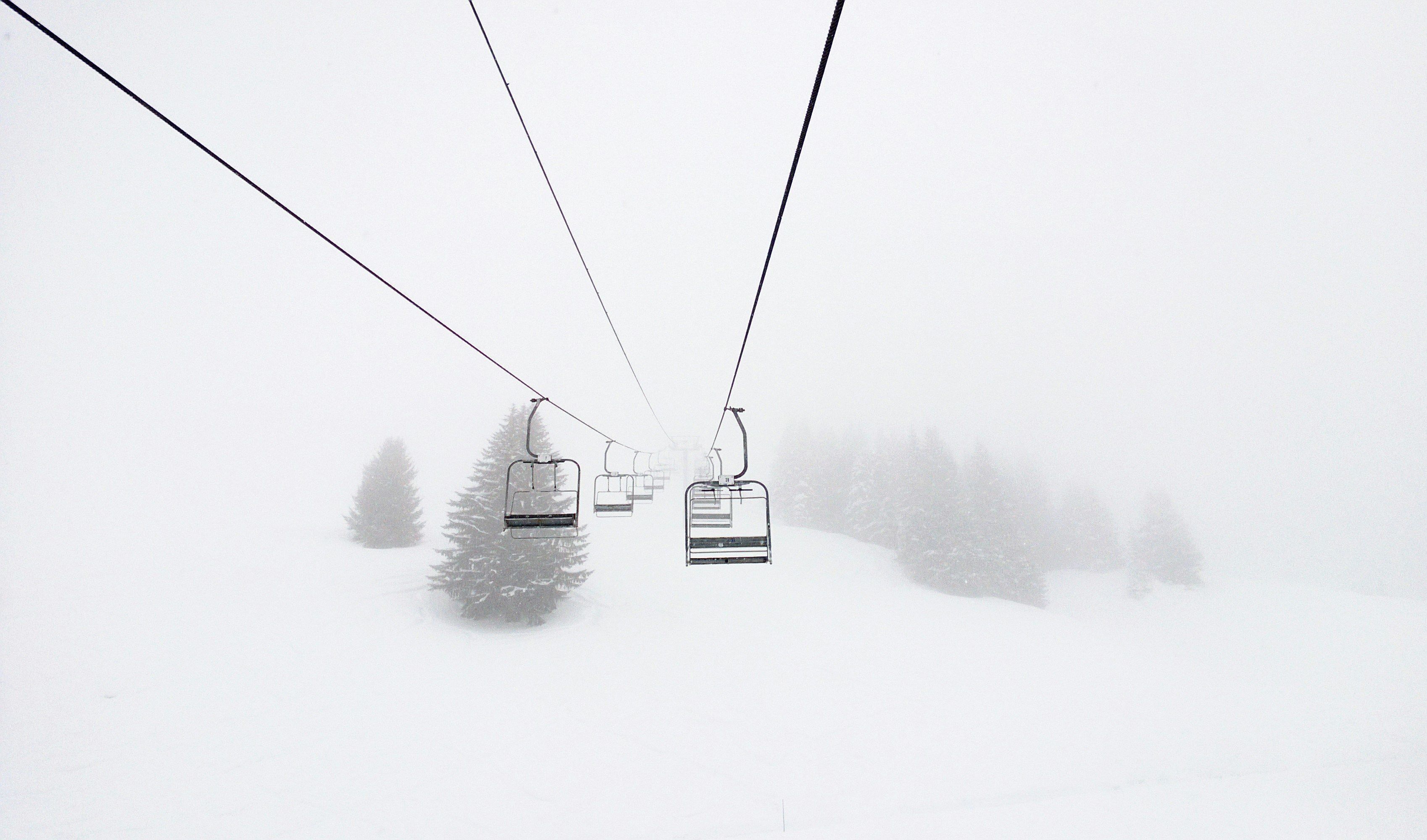 A ski lift in a snowy landscape with trees in the background.