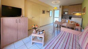 Ein gemütlicher Wohnbereich mit Fernseher, Sofa, Esstisch und Küchenzeile.