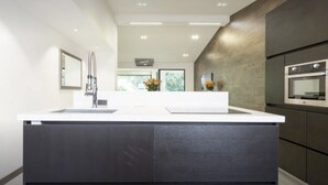 A modern kitchen with a central island, dark cabinetry, and a stainless steel oven.