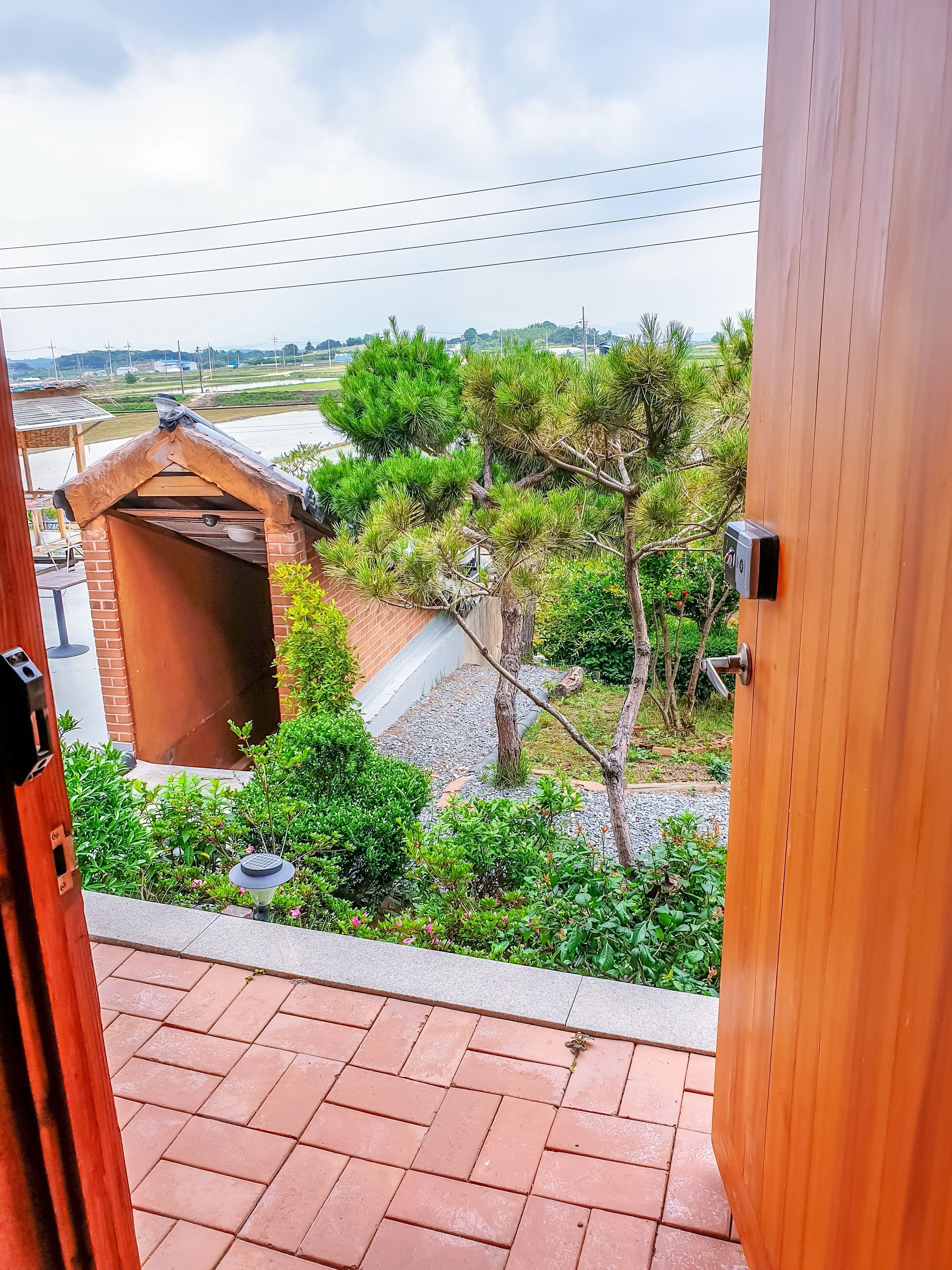 Un balcón con vistas a un jardín, una estructura de madera y una puerta.