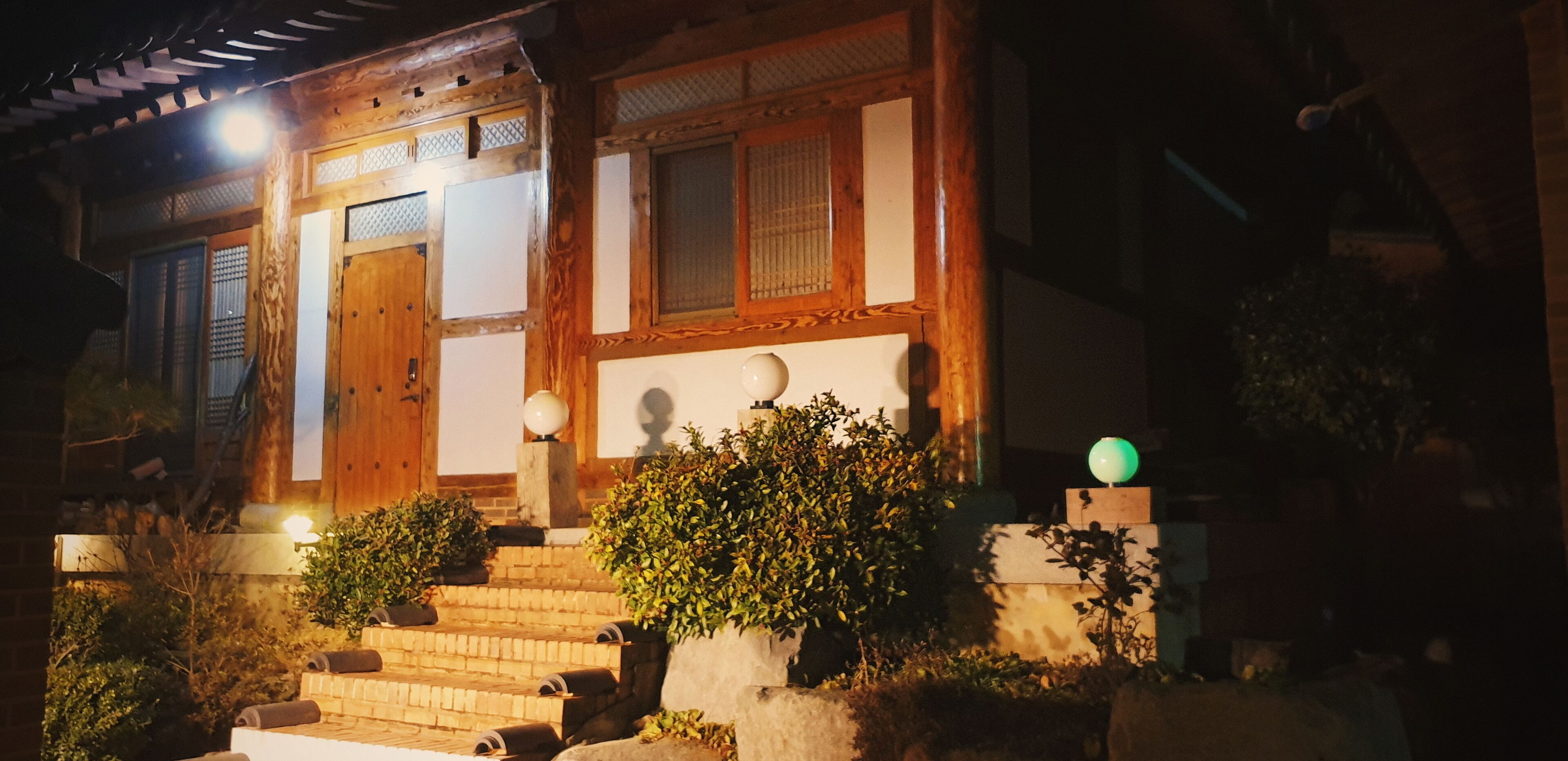 A traditional wooden building with a wooden door, windows with lattice designs, and a staircase leading to the entrance.