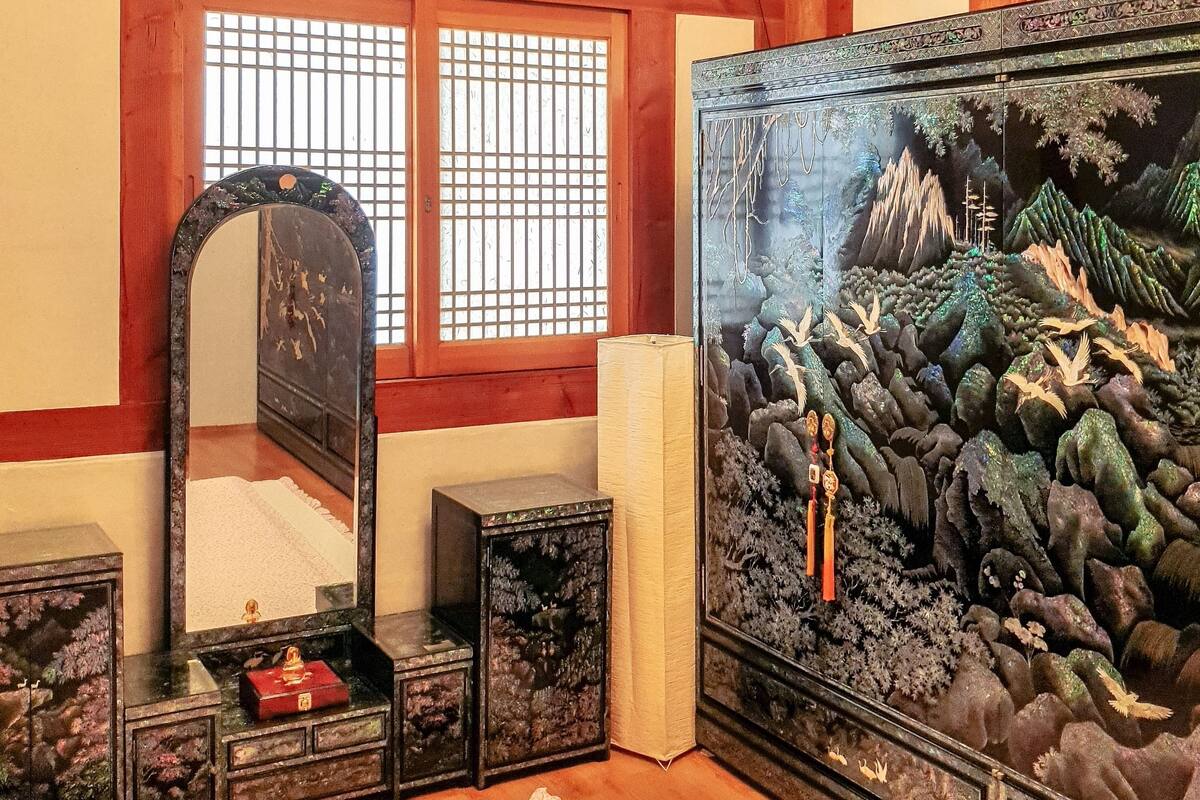 Une pièce de style japonais traditionnel, avec un sol recouvert de tatamis, un paravent shoji, une grande peinture et un miroir.