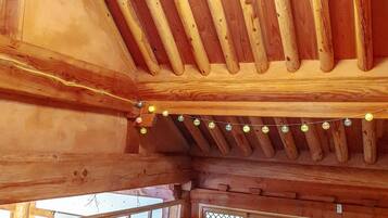 A wooden interior with a sloped ceiling, string lights, and a view through a window.
