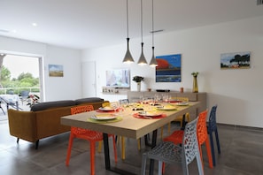 A modern dining area with a long table set for a meal, surrounded by colorful chairs. - Beautiful villa 5 minutes from the beach. Pets welcome. (PLAISANCE)