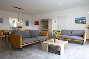A modern living room with two sofas, a coffee table, and a dining area with chairs and a table.