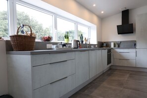 A modern kitchen with a large window, a built-in oven, and a flat-screen TV mounted on the wall.