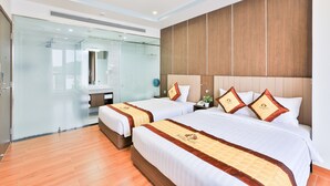 A hotel room with two beds, a glass shower enclosure, wooden paneling on the walls, and a tiled floor. - Prague Saigon Airport Hotel (Ho Chi Minh City)