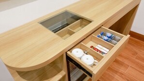 A kitchen with a wooden countertop, a glass water dispenser, and a drawer with various items. - Prague Saigon Airport Hotel (Ho Chi Minh City)